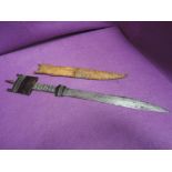 A Nigerian short sword with decorated handle and leather scabbard