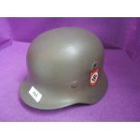 A World War II helmet with replacement liner, chin strap and printed badges