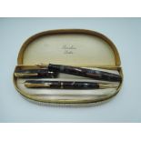 A boxed Burnham fountain pen and propelling pencil set, in burgundy and grey marble, with medium