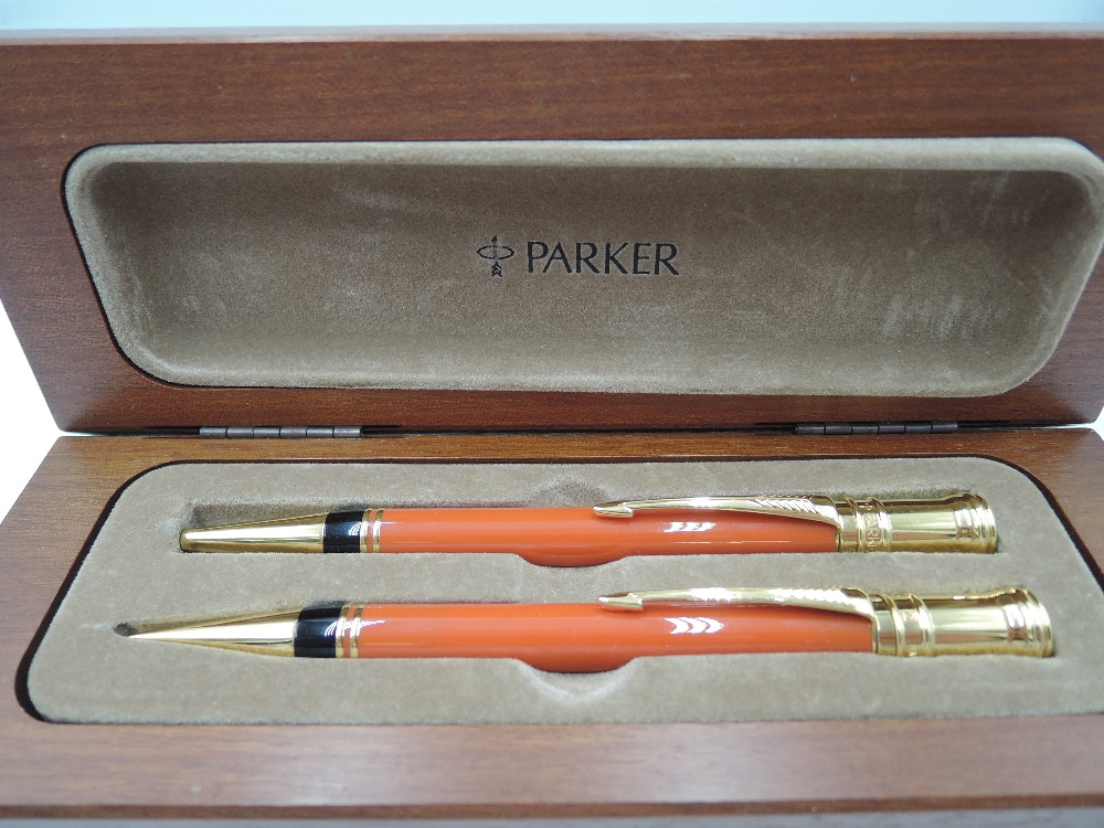 A Parker Duofold propelling pencil and ballpoint pen set in orange, in wooden presentation box