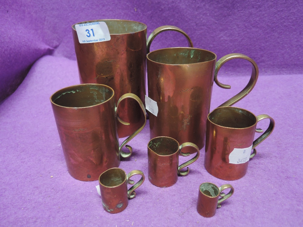 A selection of graduated copper and brass handled cups