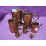 A selection of graduated copper and brass handled cups