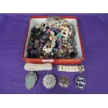 A small selection of costume jewellery including strings of beads and brooches