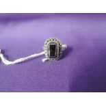 A lady's dress ring having a rectangular hematite stone cluster on a white metal loop stamped