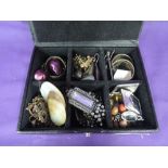 A small black travel jewellery case containing a selection of costume earrings