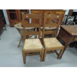 A pair of modern oak ladderback dining chairs having rush seats