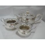 A silver three piece tea set of squat urn form having moulded and pierced decoration to rim,