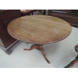 A late 18th/early 19th century oak pedestal table having circular top on turned column and triple