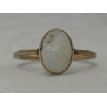 A lady's dress ring having an oval opal in a collared mount on a yellow metal loop stamped 9ct, size
