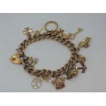 A yellow metal curb link charm bracelet stamped 9ct having 13 yellow metal and 9ct gold charms and