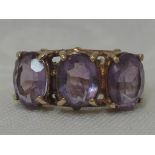 A lady's dress ring having three oval amethysts in claw set raised mounts on a 9ct gold loop, size
