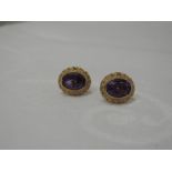 A pair of oval amethyst stud earrings in decorative 9ct gold twist mounts