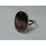 A lady's dress ring having an oval Blue John panel in a white metal collared mount to open shoulders