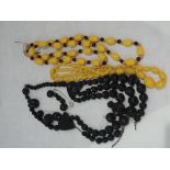 A broken three string carved jet mourning necklace and two vintage strings of yellow beads