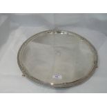 A silver salver of circular form having a raised rim with moulded decoration, quatrefoil paw feet