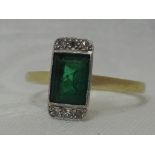A lady's dress ring of Art Deco style having an emerald style baguette cut stone flanked by