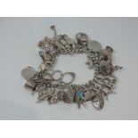 A silver charm bracelet having approx 35 white metal and silver charms including golf bag, shell,