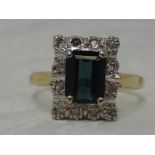 A lady's dress ring having a baguette cut green topaz style stone within a rectangular diamond set