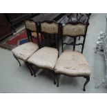 A set of three late Victorian mahogany salon chairs having crest and upholstered panel backs and