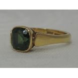 A lady's dress ring having a green sapphire solitaire in a collared mount to but shoulders on an
