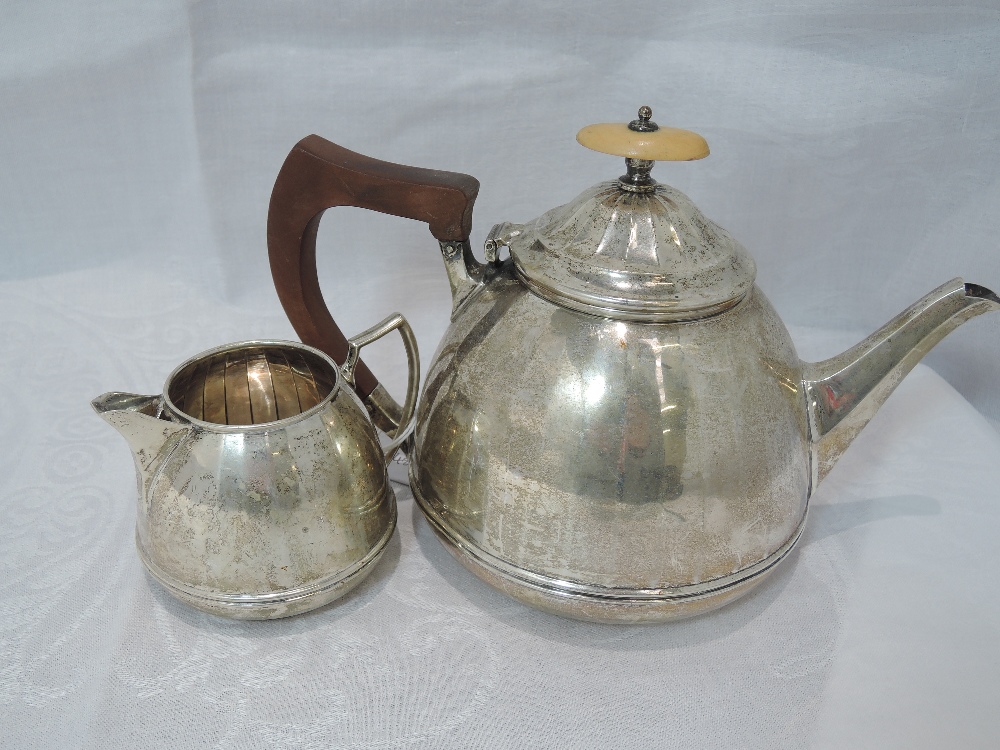 A silver teapot and cream jug having facetted decoration and soft wood handle, Birmingham 1934,