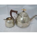 A silver teapot and cream jug having facetted decoration and soft wood handle, Birmingham 1934,
