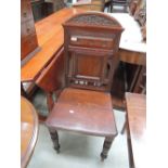 A late Victorian mahogany hall chair having crest spindle and panel back, with solid seat and turned