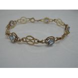 A 9ct gold articulated bracelet having five aquamarine stones on alternate linked circular panels