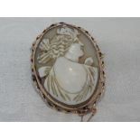 A conche shell cameo brooch depicting a Grecian maiden in a yellow metal mount having twist