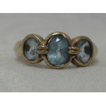 A lady's dress ring having three oval blue topaz in collared mounts on a 9ct gold loop, size M/N