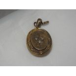 A yellow metal locket having engraved and moulded decoration with a trio of old cut diamonds, no