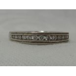 A lady's half eternity ring having 14 diamond chips in a channel set mount on a white metal loop