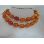 A string of graduated oval butterscotch amber beads having a 9ct gold clasp, approx 68g & 30'