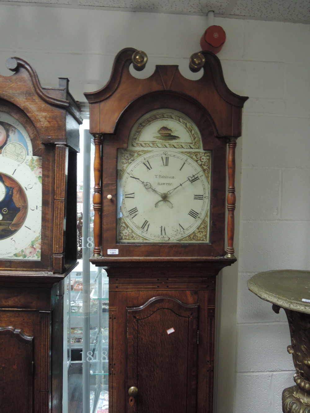 An early 19th century oak longcase clock having swan neck and pillar hood, containing painted dial