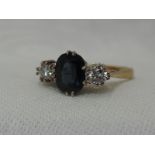 A lady's dress ring having an oval central sapphire flanked by two diamonds each approx 0.128ct in a