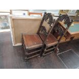 A pair of late Victorian oak carolean style hall chairs having carved moon face and cloud rail