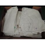 A box full of antique table linen and bed linen, including some intricately embroidered table