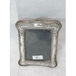 A silver and velvet photograph frame of shaped rectangular form having moulded foliate decoration,