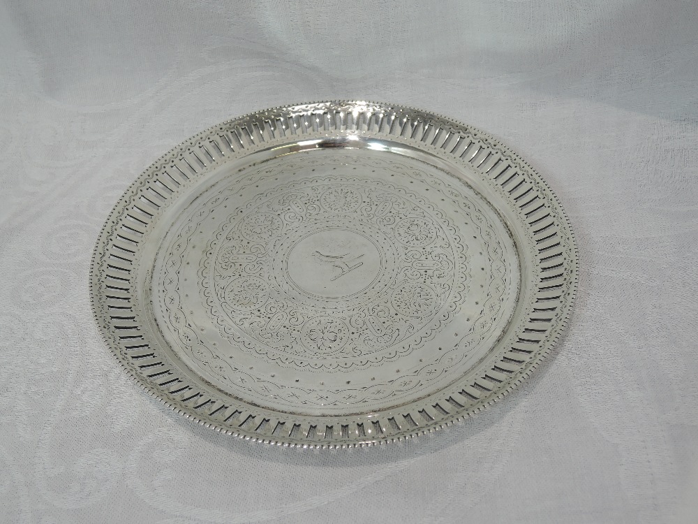 A Victorian silver card tray having pierced rim, extensive engraved decoration and bun feet,