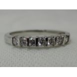 A lady's half eternity ring having seven diamond chips in a tension mount on a platinum loop, size