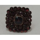 A lady's dress ring having a large Bohemian garnet set square cluster on a silver gilt loop