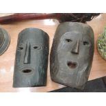 Two vintage tribal masks, on brown wood, and black wood