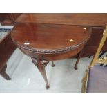 A mid 20th century mahogany carved table having demi lune fold over baize top on cabriole gate leg