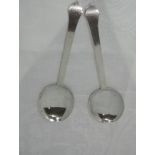 A pair of Artisan style silver dessert serving spoons of plain form having shaped terminals, stamped