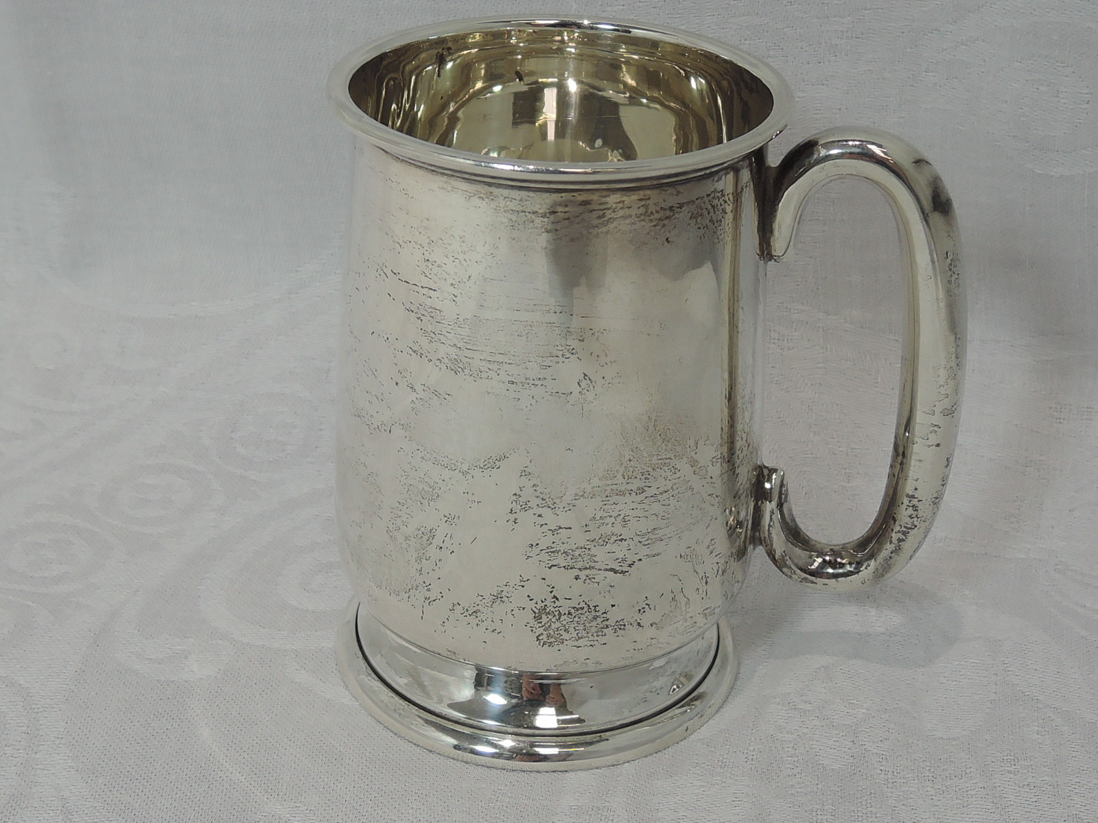 A small silver tankard of plain baluster form having moulded handle and pedestal foot, Chester 1940,