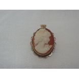 A conche shell cameo pendant/brooch depicting a maiden in profile in a decorative 9ct gold mount