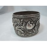A white metal hinged bangle of broad form having extensive moulded water lily decoration, no marks