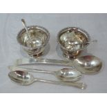 A pair of silver salts of plain circular urn form having decorative rims and matching spoons,