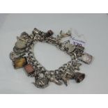 An HM silver charm bracelet having 23 white metal and HM silver charms including cased 10 shilling