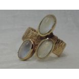A lady's dress ring of stylised form having three oval moonstones in collared mounts on a bark